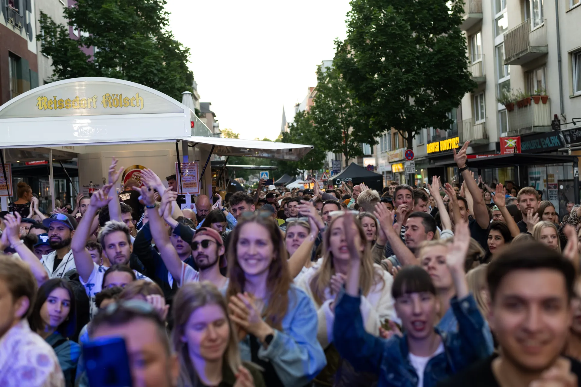 Eine grosse, feiernde Menschenmenge steht auf der Bonner Strasse beim Sudstadtfest und jubelt mit erhobenen Handen.