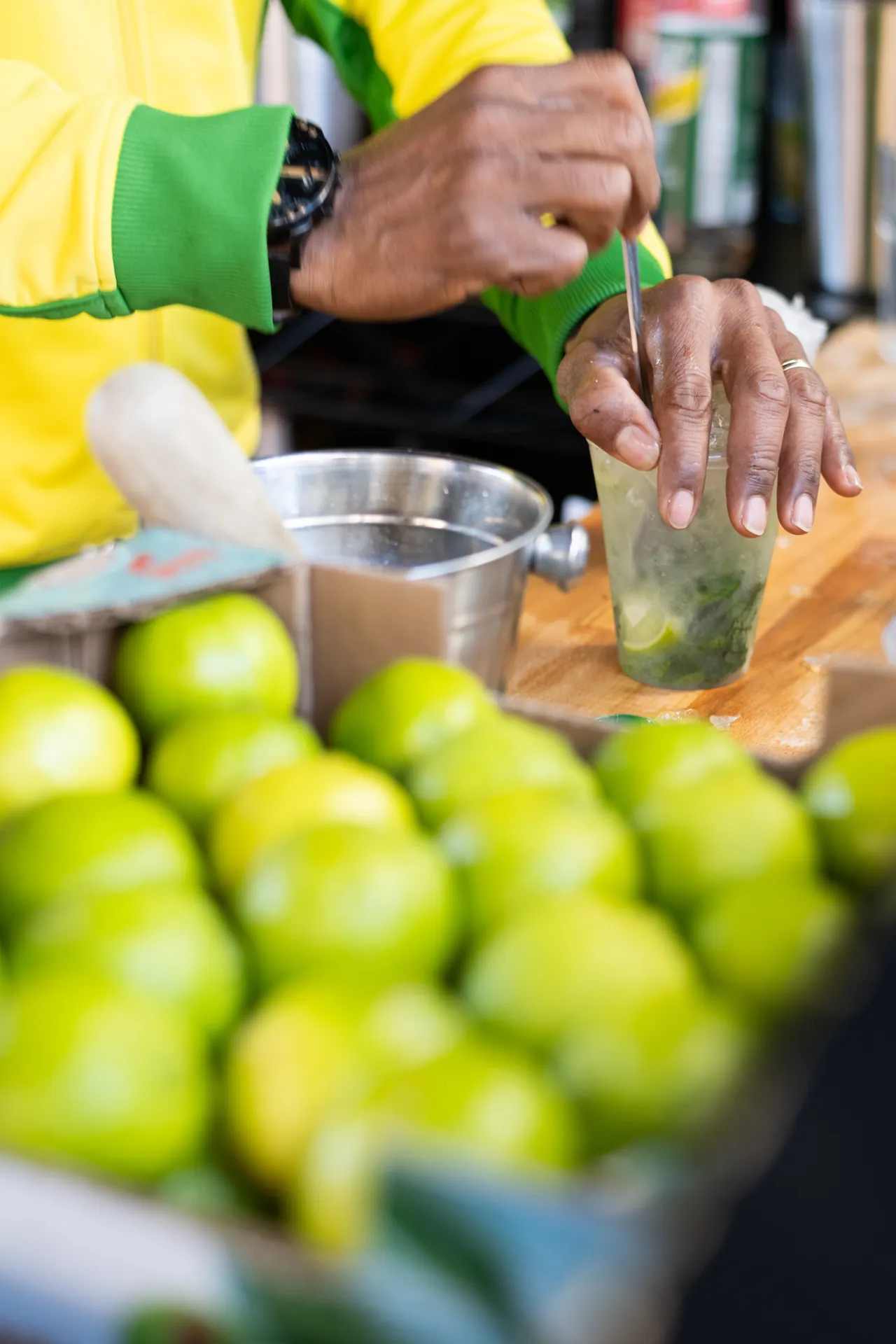 Verkäufer bereitet einen Caipirinha mit frischen Limetten und Minze zu
