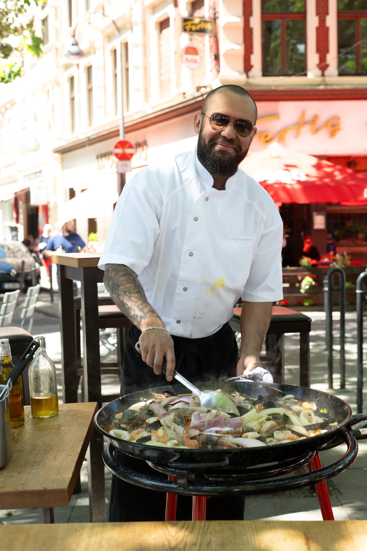 Ein bartiger Koch mit Sonnenbrille bereitet auf dem Sudstadtfest in einer grossen Pfanne eine Paella zu.