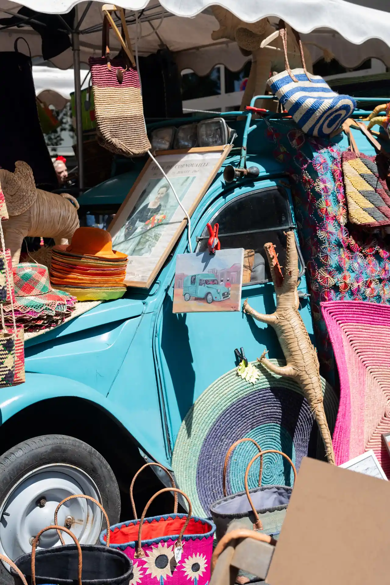Bunter Verkaufsstand mit Taschen und Accessoires an einem türkisen Oldtimer